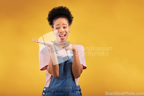 Image of Branding, advertising and a black woman pointing to her palm for the promotion of a product on a yellow background in studio. Smile, marketing or space with a happy young female brand ambassador