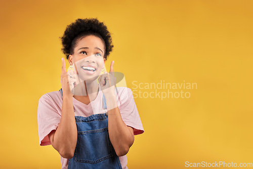 Image of Smile, pointing and mockup with a black woman on a yellow background in studio for advertising or marketing. Sale, presentation or information with a happy young female brand ambassador showing space