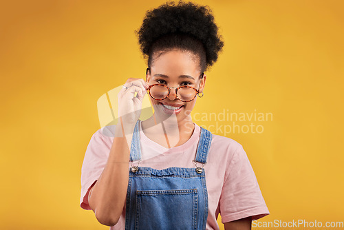 Image of Portrait, glasses and happy with a black woman on a yellow background in studio for vision. Fashion, eyewear and smile with a young afro female nerd at the optometrist for prescription frame lenses