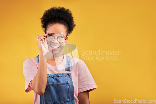 Image of Smile, glasses and vision with a black woman nerd on a yellow background in studio for style. Fashion, eyewear and a happy young afro female geek at the optometrist for prescription frame lenses