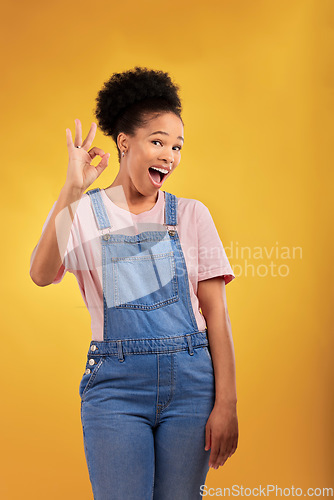 Image of Portrait, okay and hand gesture with an excited black woman in studio on a yellow background. Smile, wow and perfect with a happy young female person showing a sign of support, feedback or review