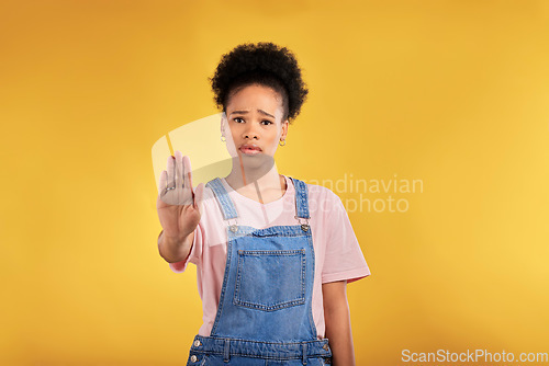 Image of Stop, hand and warning with portrait of black woman in studio for emoji, no and voice. Rejection, opinion and sign with person on yellow background for protest, discrimination and forbidden icon