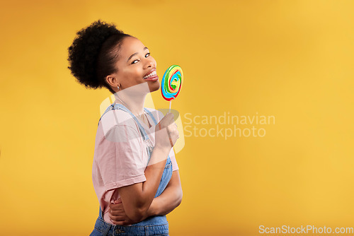 Image of Black woman, portrait and eating candy or lollipop in studio on yellow background and sweets, dessert or food with sugar. Gen z, girl and guilty pleasure in delicious treats, snack or product