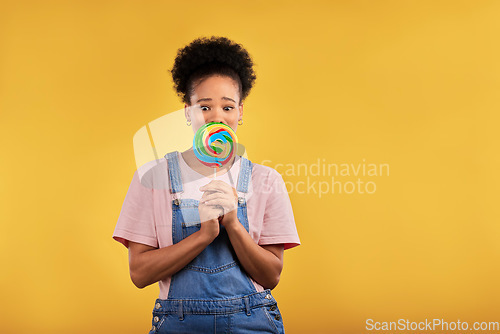 Image of Black woman, portrait with candy or lollipop in studio on yellow background and eating sweets, dessert or food with sugar. Gen z, girl and guilty pleasure in delicious treats, snack or product