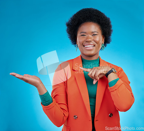 Image of Happy black woman, portrait and pointing to palm for advertising against a blue studio background. Face of African female person show advertisement in marketing, list or sale discount on mockup space