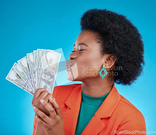 Image of Cash, kiss and a black woman lottery winner on a blue background in studio holding money for finance. Savings, investment or economy growth with a young female person posing for financial freedom