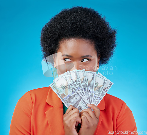 Image of Cash, hide and a black woman lottery winner on a blue background in studio holding money for finance. Savings, investment or economy growth with a young female person excited for financial freedom