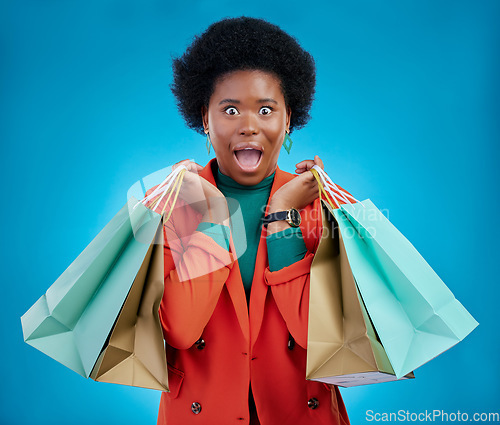 Image of Shopping bag, wow portrait and woman for fashion discount, giveaway or retail sales on blue background. Happy, excited or surprise face of customer, winner or african person in clothes deal in studio