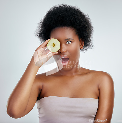 Image of Skincare, apple and portrait of a woman in studio with a natural, organic and beauty face routine. Shock, wellness and African female model with slice of fruit for facial treatment by gray background