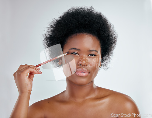 Image of Black woman, portrait and makeup brush on eyes for skincare beauty against a white studio background. Face of African female person applying eye product, cosmetics or lashes for facial treatment