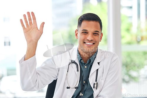 Image of Doctor, portrait and wave with smile at desk for video call, telehealth service and hello for kindness. Young medic man, sign language and respect with introduction, happy and webinar for healthcare