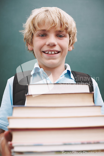 Image of I cant wait to read them all. A cute young boy carrying a large stack of books and smiling at you.