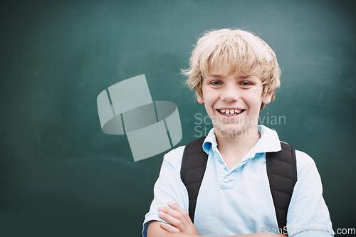 Image of Super happy to be at school. A young schoolboy crossing his arms while standing alongside copyspace at a blackboard.