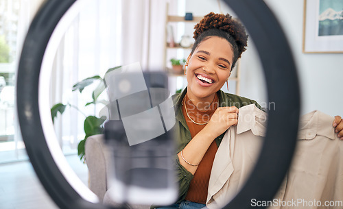 Image of Fashion, social media and a black woman content creator unboxing a clothes outfit in her home. Live streaming, brand deal and a happy female influencer recording a broadcast for subscription service