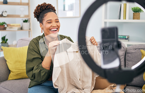 Image of Fashion, live streaming and a black woman content creator unboxing a clothes outfit in her home. Social media, brand deal and a happy female influencer recording a broadcast for subscription service