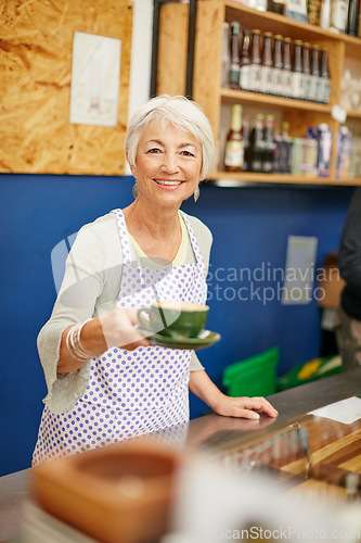 Image of Made to order. Shot of a senior woman serving coffee in a cafe.