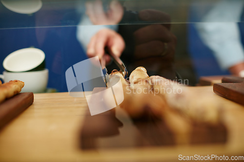 Image of Only the freshest will do. Cropped shot of a deli worker choosing a bread stick from the display.