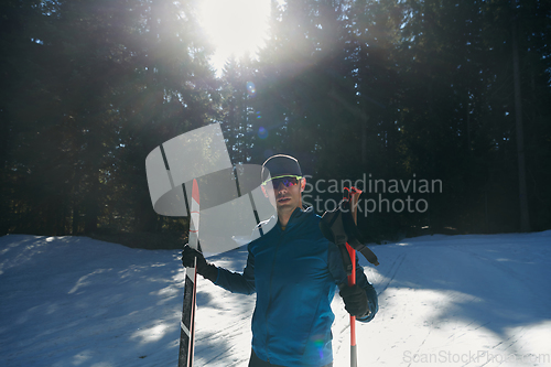 Image of Portrait handsome male athlete with cross country skis in hands and goggles, training in snowy forest. Healthy winter lifestyle concept.