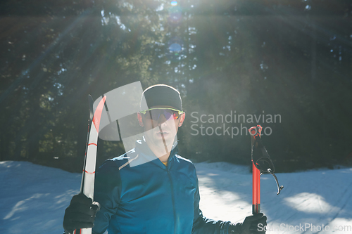 Image of Portrait handsome male athlete with cross country skis in hands and goggles, training in snowy forest. Healthy winter lifestyle concept.