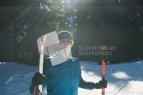 Image of Portrait handsome male athlete with cross country skis in hands and goggles, training in snowy forest. Healthy winter lifestyle concept.