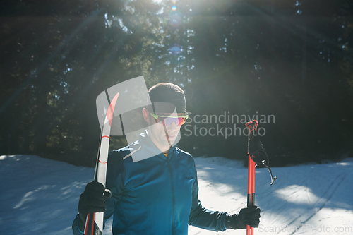 Image of Portrait handsome male athlete with cross country skis in hands and goggles, training in snowy forest. Healthy winter lifestyle concept.