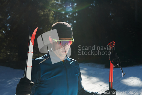 Image of Portrait handsome male athlete with cross country skis in hands and goggles, training in snowy forest. Healthy winter lifestyle concept.