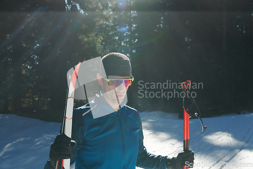 Image of Portrait handsome male athlete with cross country skis in hands and goggles, training in snowy forest. Healthy winter lifestyle concept.