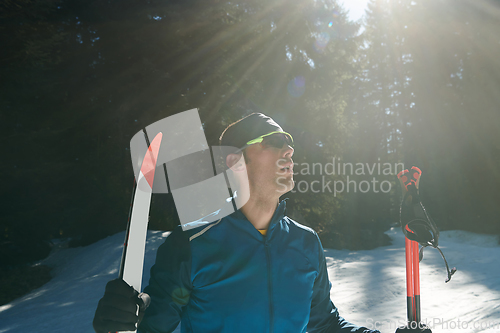 Image of Portrait handsome male athlete with cross country skis in hands and goggles, training in snowy forest. Healthy winter lifestyle concept.