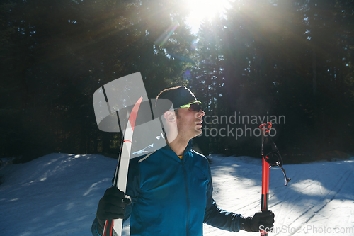 Image of Portrait handsome male athlete with cross country skis in hands and goggles, training in snowy forest. Healthy winter lifestyle concept.