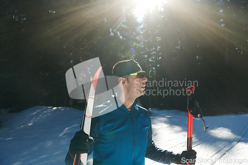 Image of Portrait handsome male athlete with cross country skis in hands and goggles, training in snowy forest. Healthy winter lifestyle concept.