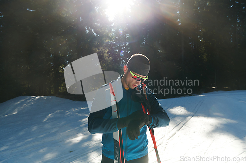 Image of Portrait handsome male athlete with cross country skis in hands and goggles, training in snowy forest. Healthy winter lifestyle concept.