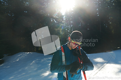 Image of Portrait handsome male athlete with cross country skis in hands and goggles, training in snowy forest. Healthy winter lifestyle concept.