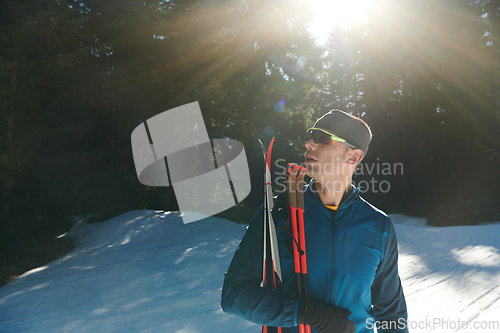 Image of Portrait handsome male athlete with cross country skis in hands and goggles, training in snowy forest. Healthy winter lifestyle concept.