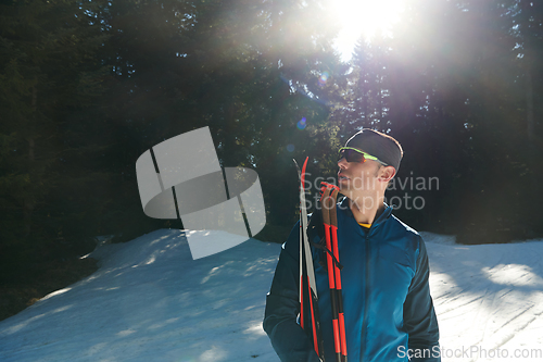 Image of Portrait handsome male athlete with cross country skis in hands and goggles, training in snowy forest. Healthy winter lifestyle concept.