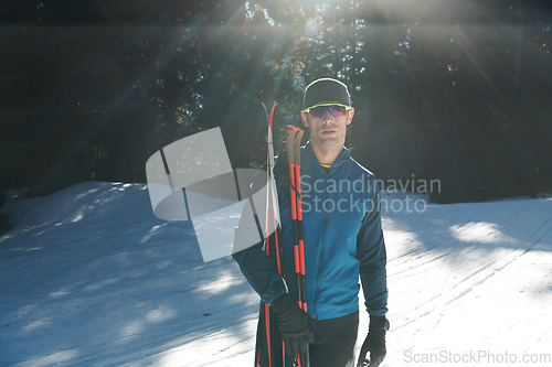 Image of Portrait handsome male athlete with cross country skis in hands and goggles, training in snowy forest. Healthy winter lifestyle concept.