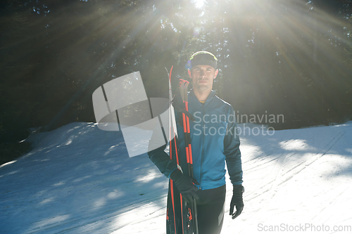 Image of Portrait handsome male athlete with cross country skis in hands and goggles, training in snowy forest. Healthy winter lifestyle concept.