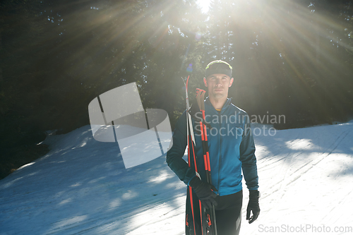 Image of Portrait handsome male athlete with cross country skis in hands and goggles, training in snowy forest. Healthy winter lifestyle concept.