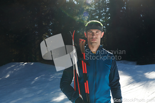 Image of Portrait handsome male athlete with cross country skis in hands and goggles, training in snowy forest. Healthy winter lifestyle concept.