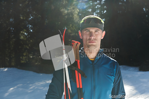 Image of Portrait handsome male athlete with cross country skis in hands and goggles, training in snowy forest. Healthy winter lifestyle concept.