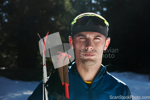 Image of Portrait handsome male athlete with cross country skis in hands and goggles, training in snowy forest. Healthy winter lifestyle concept.