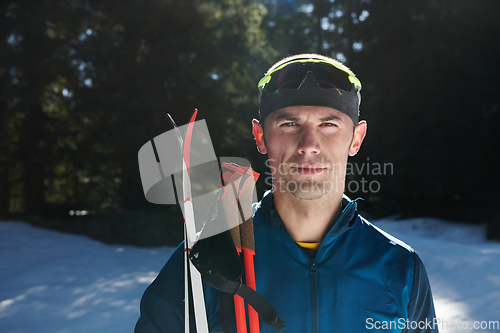 Image of Portrait handsome male athlete with cross country skis in hands and goggles, training in snowy forest. Healthy winter lifestyle concept.