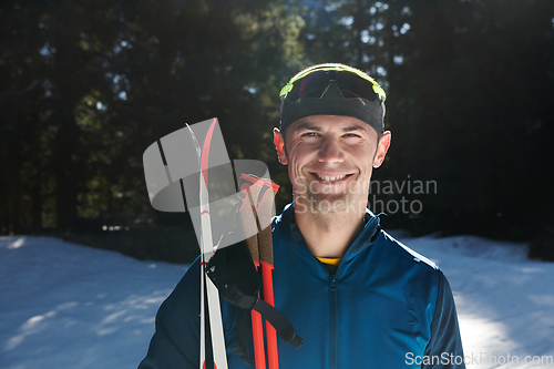 Image of Portrait handsome male athlete with cross country skis in hands and goggles, training in snowy forest. Healthy winter lifestyle concept.