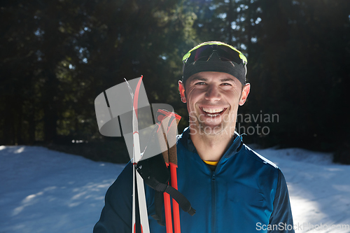 Image of Portrait handsome male athlete with cross country skis in hands and goggles, training in snowy forest. Healthy winter lifestyle concept.