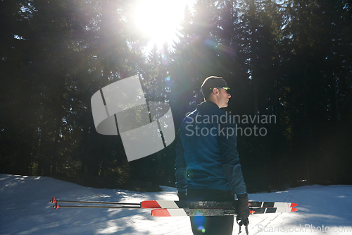 Image of Portrait handsome male athlete with cross country skis in hands and goggles, training in snowy forest. Healthy winter lifestyle concept.