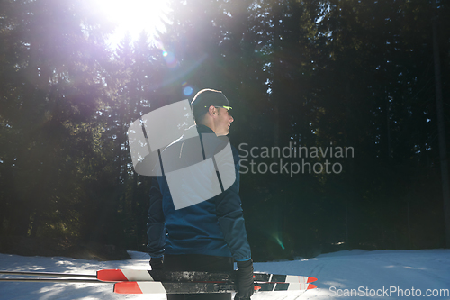 Image of Portrait handsome male athlete with cross country skis in hands and goggles, training in snowy forest. Healthy winter lifestyle concept.