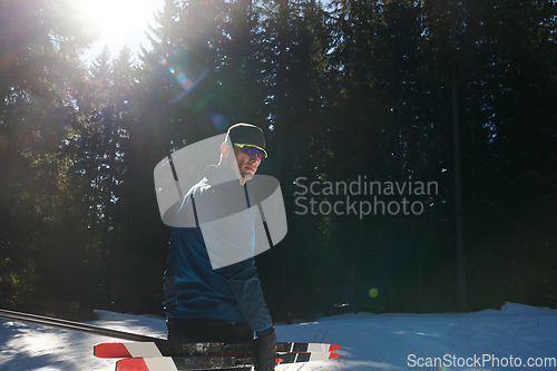 Image of Portrait handsome male athlete with cross country skis in hands and goggles, training in snowy forest. Healthy winter lifestyle concept.