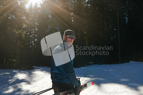 Image of Portrait handsome male athlete with cross country skis in hands and goggles, training in snowy forest. Healthy winter lifestyle concept.