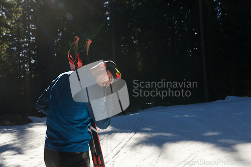 Image of Portrait handsome male athlete with cross country skis in hands and goggles, training in snowy forest. Healthy winter lifestyle concept.