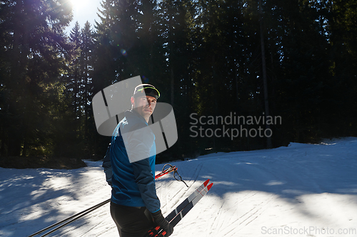 Image of Portrait handsome male athlete with cross country skis in hands and goggles, training in snowy forest. Healthy winter lifestyle concept.