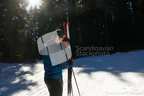 Image of Portrait handsome male athlete with cross country skis in hands and goggles, training in snowy forest. Healthy winter lifestyle concept.